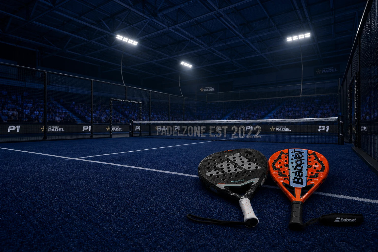 Two padel rackets staged on a blue indoor court